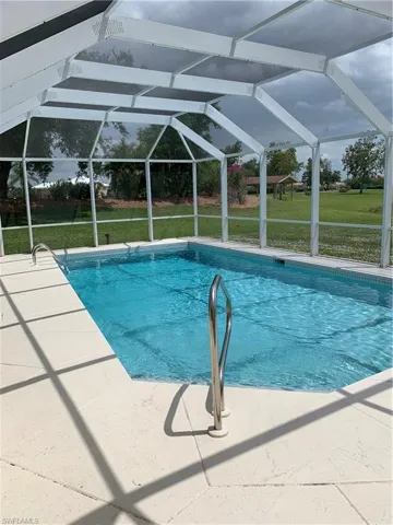 Outdoor pool featuring a lawn, glass enclosure, and a patio