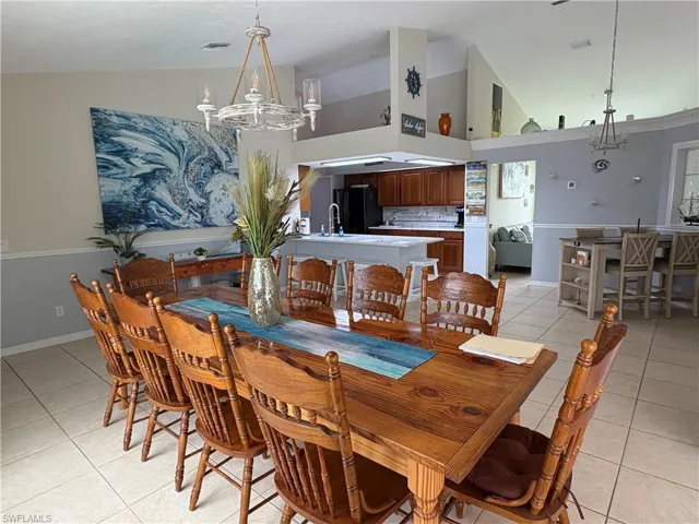 Dining space featuring a chandelier, light tile patterned flooring, high vaulted ceiling, and baseboards
