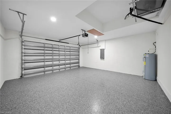 Garage featuring water heater, a garage door opener, and electric panel