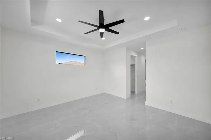 Unfurnished room with ceiling fan and a tray ceiling