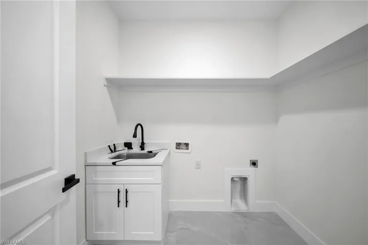 Clothes washing area featuring electric dryer hookup, washer hookup, sink, and cabinets