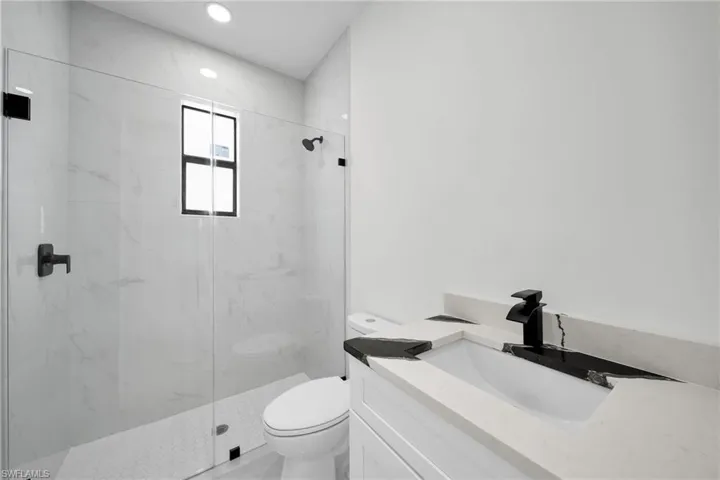 Bathroom with vanity, toilet, and a shower with shower door
