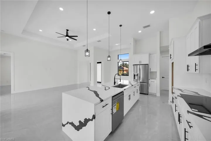Kitchen featuring pendant lighting, sink, an island with sink, stainless steel appliances, and ceiling fan