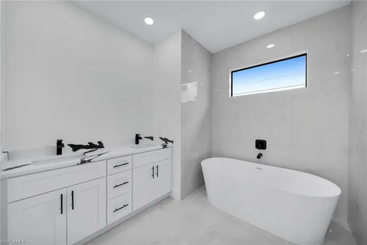 Bathroom with tile walls, vanity, and a bathing tub
