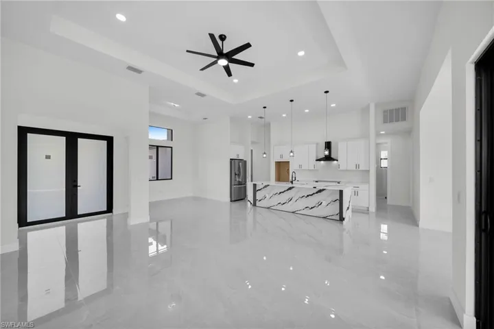 Unfurnished living room with ceiling fan, a tray ceiling, and sink