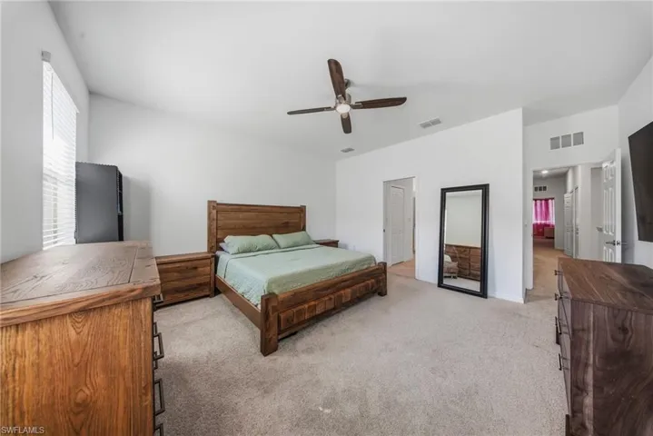 Bedroom with light colored carpet and a ceiling fan