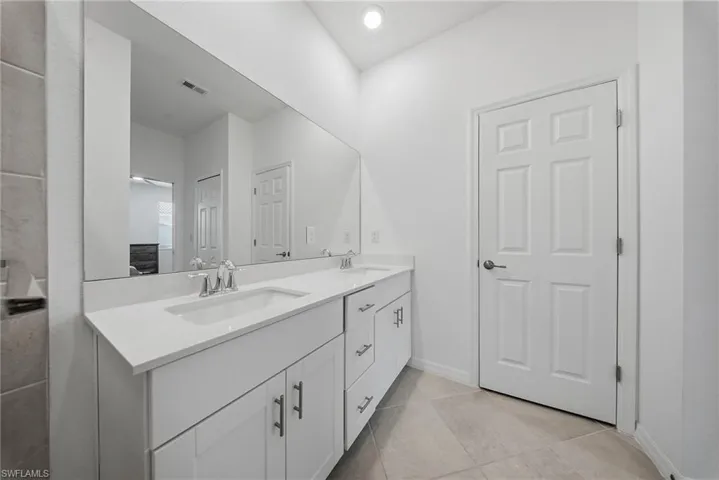 Bathroom featuring double vanity and light tile patterned floors