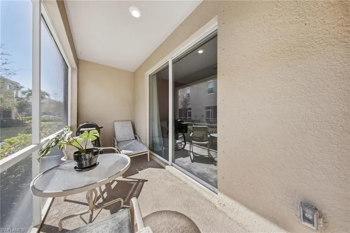 Sunroom featuring a textured wall, recessed lighting, and a balcony