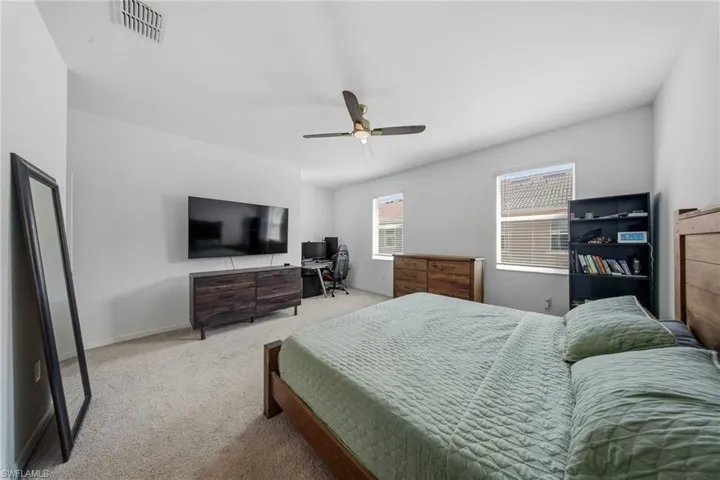 Carpeted bedroom with ceiling fan and baseboards