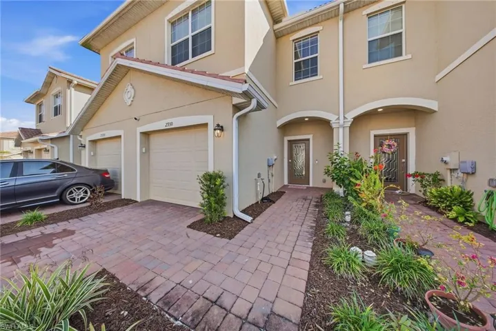View of front of house with stucco siding and decorative driveway