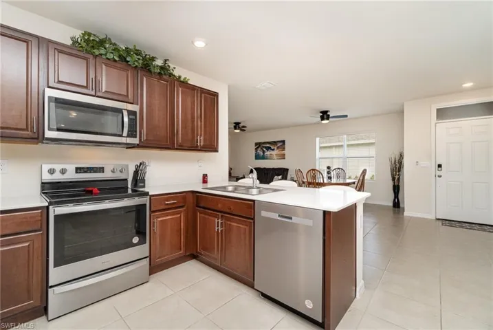 Kitchen featuring ceiling fan, sink, stainless steel appliances, kitchen peninsula, and light tile patterned floors