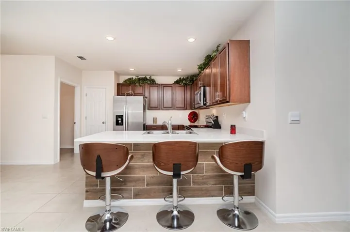 Kitchen with sink, kitchen peninsula, a breakfast bar, light tile patterned flooring, and appliances with stainless steel finishes