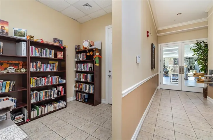 Corridor with french doors, a drop ceiling, ornamental molding, and light tile patterned flooring