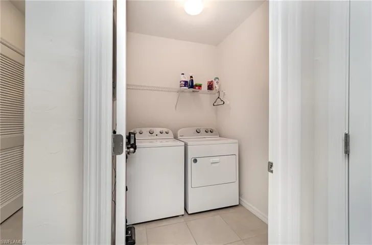 Washroom featuring light tile patterned floors and washer and clothes dryer