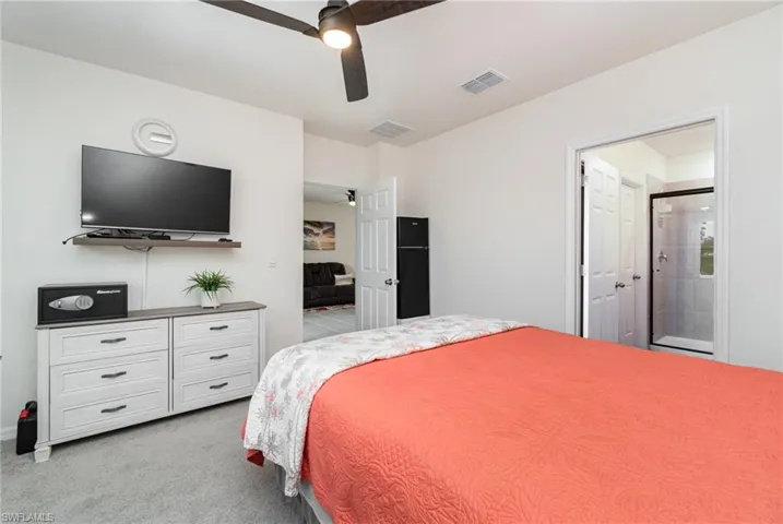 Bedroom featuring ceiling fan, light carpet, and connected bathroom