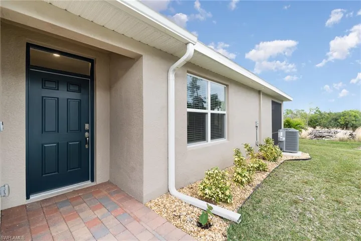 Doorway to property featuring a lawn and cooling unit