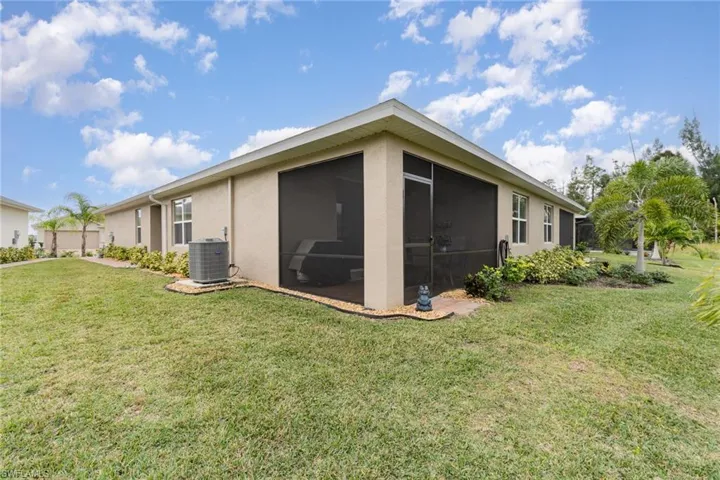 View of property exterior featuring a sunroom, central AC, and a lawn