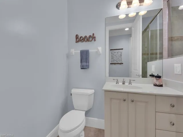 Full bathroom with vanity, a tile shower, toilet, baseboards, and tile patterned floors