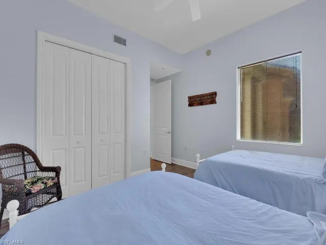 Bedroom with a closet, a ceiling fan, wood finished floors, baseboards, and visible vents