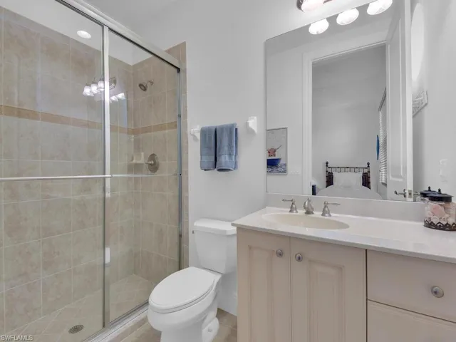 Full bath with toilet, a stall shower, and vanity