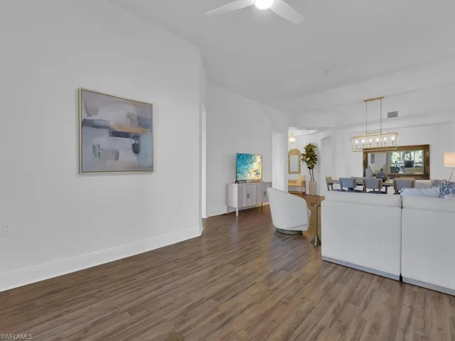 Living area with baseboards, visible vents, wood finished floors, and a ceiling fan