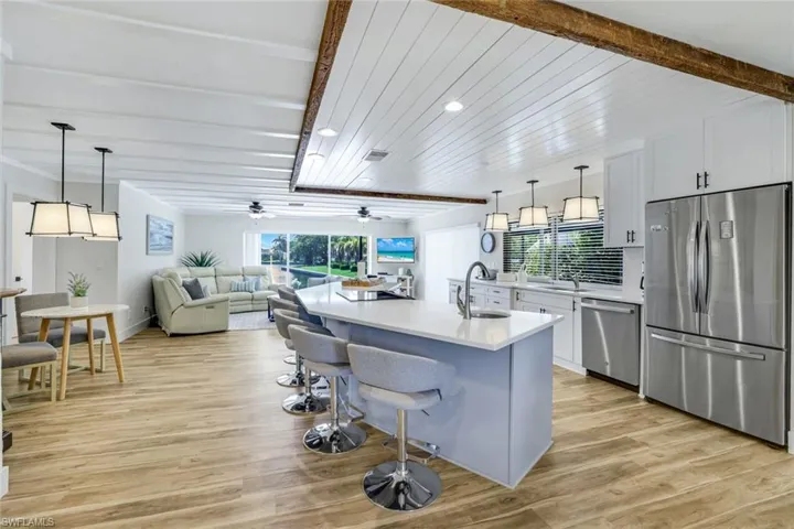 Kitchen featuring stainless steel appliances, open floor plan, pendant lighting, a breakfast bar, and ceiling fan