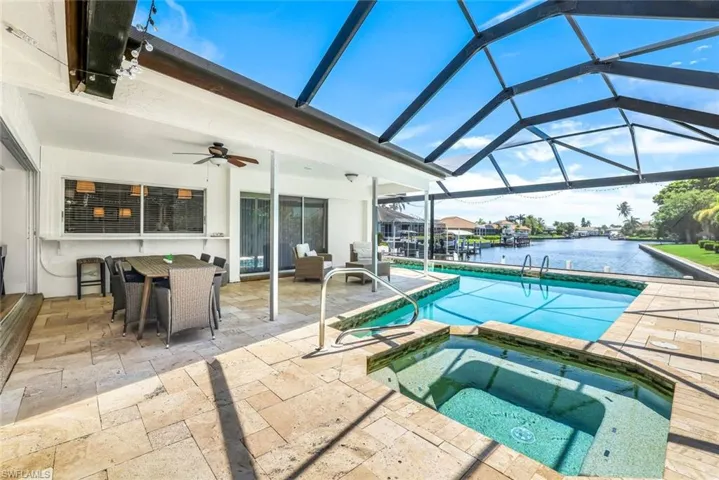 Integrated pool / hot tub with a patio, outdoor dining area, a sunroom, a lanai, and a water view