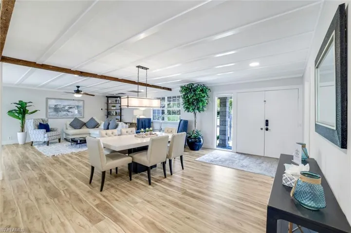 Dining room with light wood finished floors, beamed ceiling, and ceiling fan