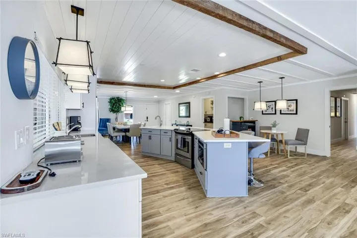 Kitchen featuring decorative light fixtures, a kitchen bar, a spacious island, light wood-style flooring, and light stone counters