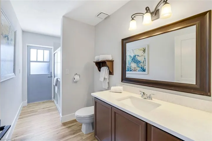 Full bathroom featuring a stall shower, vanity, and light wood-style floors