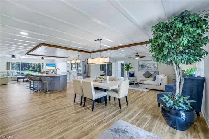 Dining area with a ceiling fan, light wood-type flooring, and beam ceiling
