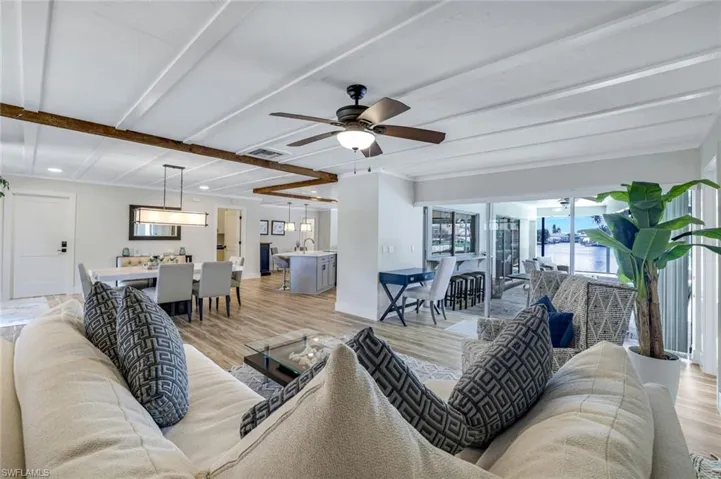 Living room featuring light wood-style floors, ceiling fan, recessed lighting, and beam ceiling