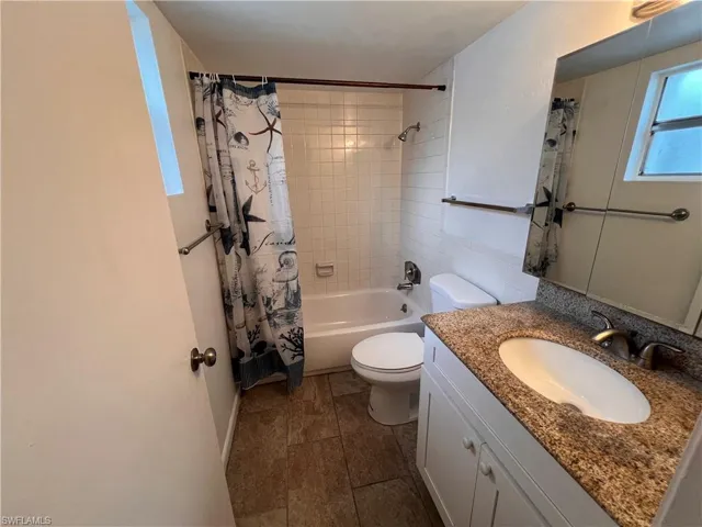 Full bathroom with vanity, toilet, tile patterned floors, and shower / bath combo