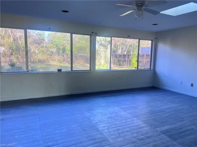 Spare room with a skylight, a ceiling fan, and baseboards