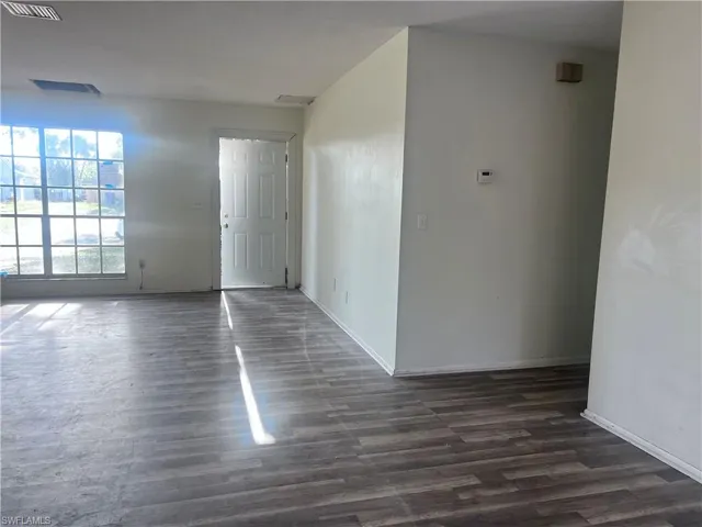 Entrance foyer with dark wood-style floors, visible vents, and baseboards