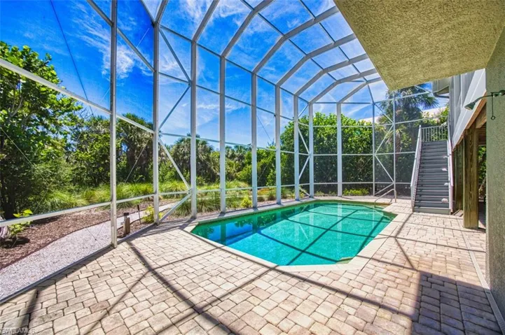 Swimming pool with a patio area, screened enclosure, and stairway
