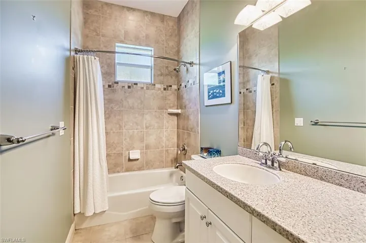 Bathroom with vanity, shower / tub combo with curtain, and tile patterned flooring