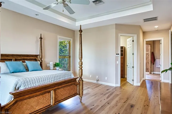 Bedroom featuring light wood-type flooring, a tray ceiling, and ceiling fan