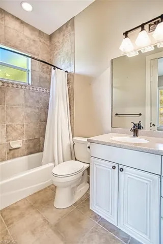 Bathroom with plenty of natural light, vanity, shower / tub combo with curtain, and tile patterned floors