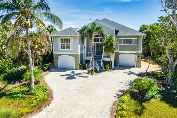 Coastal inspired elevated home featuring stairway, driveway, an attached garage, covered porch,