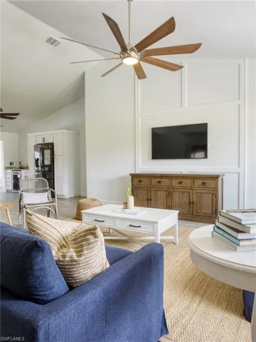 Living area featuring lofted ceiling, ceiling fan, wine cooler, and light colored carpet