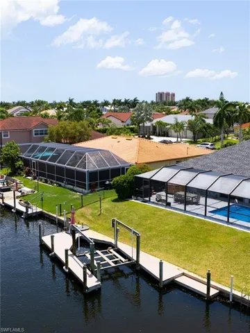 Dock with glass enclosure, a yard, a water view, boat lift, and a sunroom