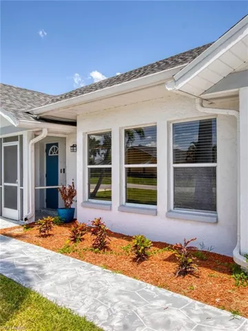 Entrance to property featuring a shingled roof and stucco siding