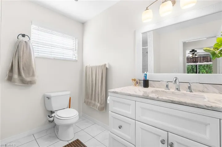 White vanity with integrated sink, chrome fixtures, and a framed mirror
