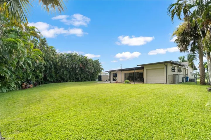 Expansive rear yard with mature landscaping and tropical trees