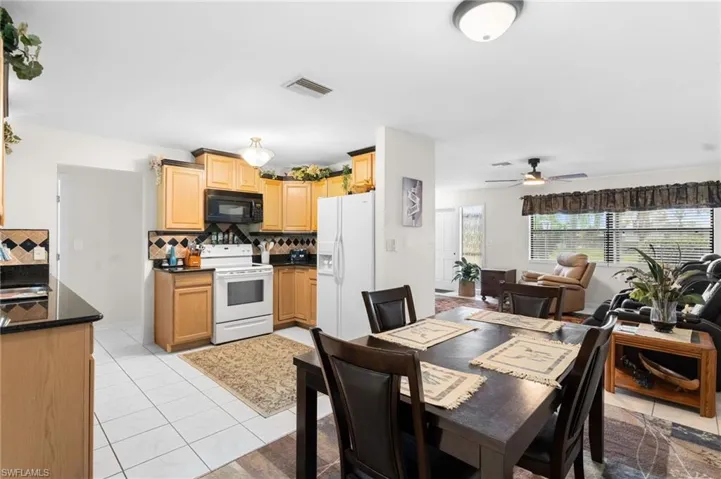 Kitchen featuring light wood cabinetry, black countertops, and a tile backsplash