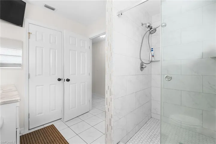 Walk-in shower with full height tile surround, glass enclosure, and hexagonal mosaic floor