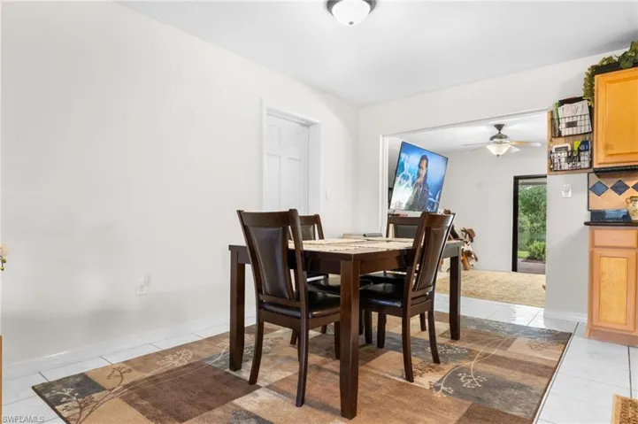 White tile flooring, ceiling-mounted light fixture, light-toned wall paint, wooden cabinetry, and a countertop surface