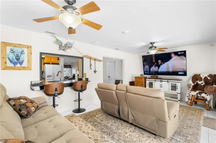 Pass-through window with black countertop, wood-finish ceiling fans, and tiled flooring