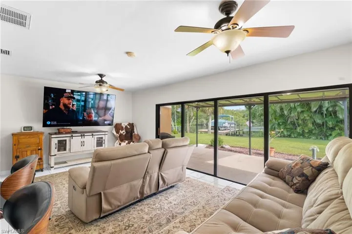 Sliding glass doors opening to outdoor patio, white tile flooring, ceiling fan, and recessed lighting